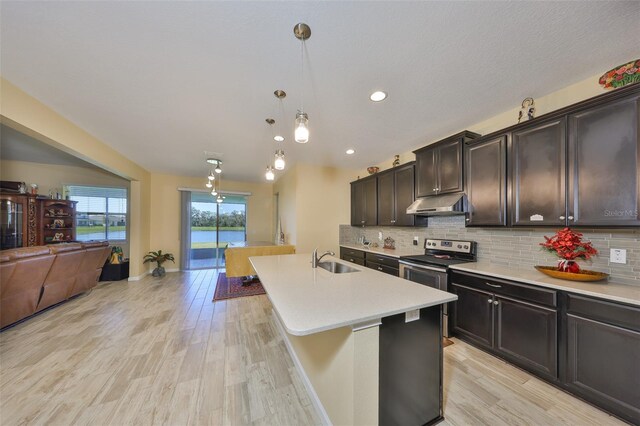 kitchen with under cabinet range hood, tasteful backsplash, open floor plan, stainless steel electric range, and light countertops