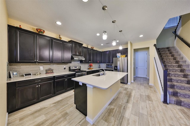 kitchen featuring under cabinet range hood, tasteful backsplash, appliances with stainless steel finishes, and light countertops