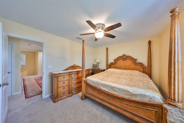 bedroom with visible vents, baseboards, light carpet, a textured ceiling, and a ceiling fan