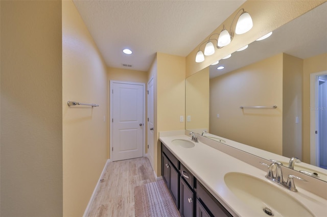 full bath with baseboards, wood finished floors, visible vents, and a sink