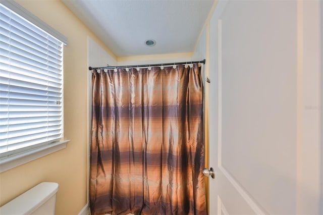 full bath featuring a shower with shower curtain and toilet