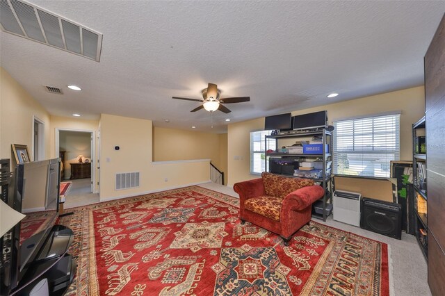 living room with visible vents, carpet floors, and a textured ceiling