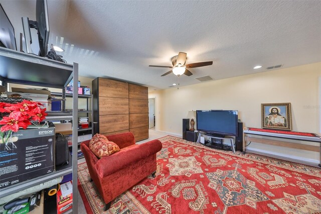 living area with ceiling fan, visible vents, and a textured ceiling