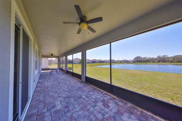 unfurnished sunroom with a water view and ceiling fan