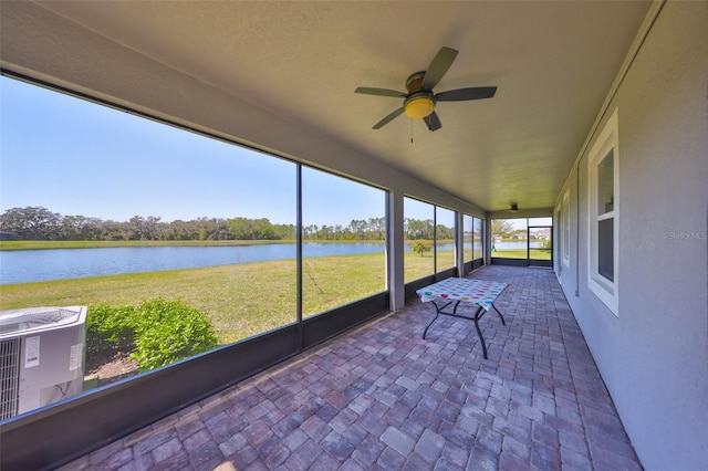 unfurnished sunroom featuring a ceiling fan and a water view