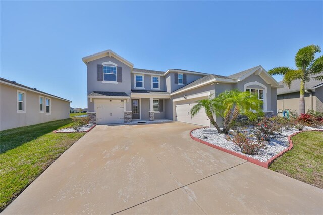 view of front facade featuring stucco siding, concrete driveway, and a front yard