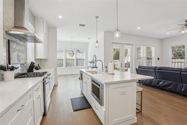 kitchen with visible vents, decorative backsplash, appliances with stainless steel finishes, wall chimney range hood, and open floor plan