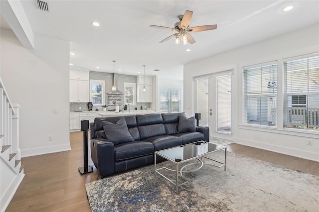 living area featuring visible vents, baseboards, ceiling fan, stairway, and wood finished floors