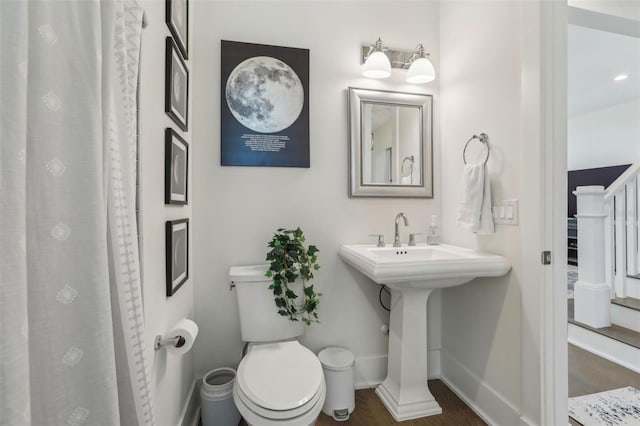 bathroom featuring curtained shower, toilet, and baseboards