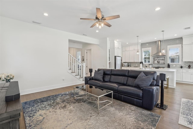 living area featuring visible vents, a ceiling fan, and wood finished floors