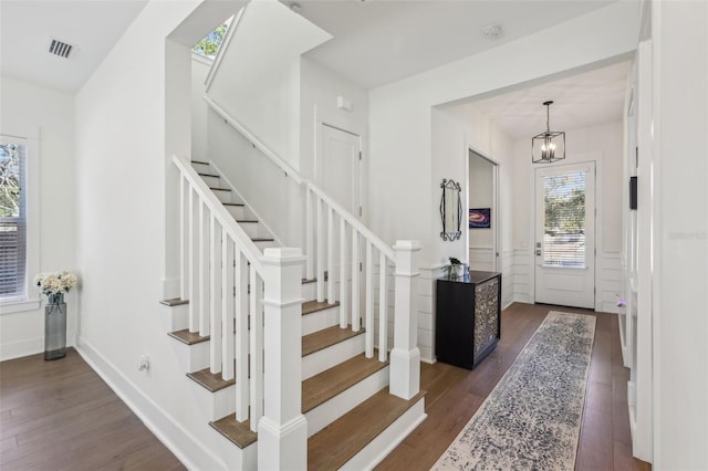 entrance foyer with dark wood-style floors, a wainscoted wall, and stairway