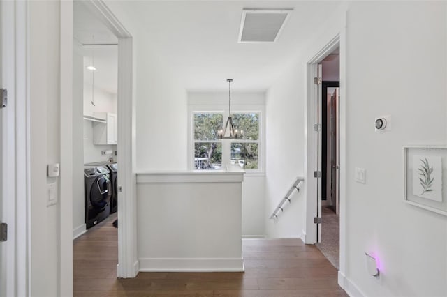 hall with an upstairs landing, visible vents, dark wood-style flooring, and washing machine and clothes dryer