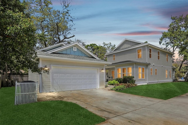 view of front facade featuring fence, board and batten siding, concrete driveway, an attached garage, and a front yard