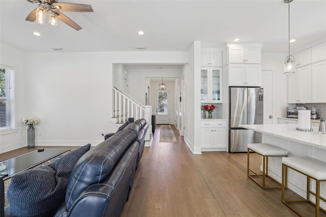 living area featuring stairway, baseboards, recessed lighting, ceiling fan, and wood-type flooring