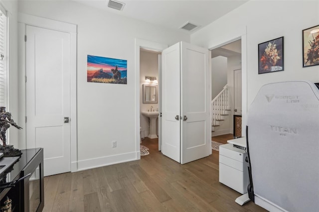 bedroom with visible vents, baseboards, light wood-style floors, and connected bathroom