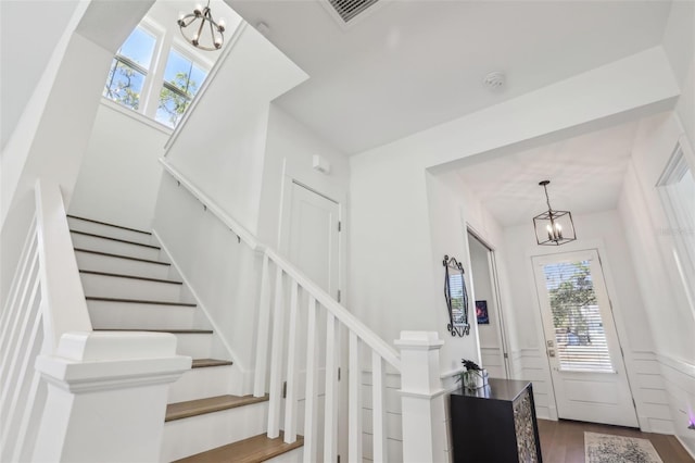 entryway with a wainscoted wall, a notable chandelier, visible vents, and stairs