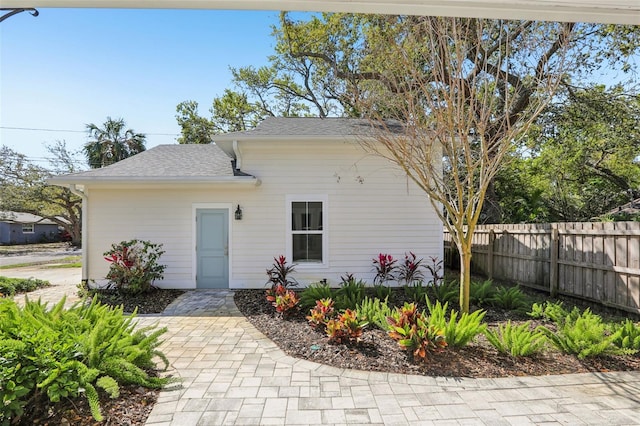 view of front of property with roof with shingles and fence