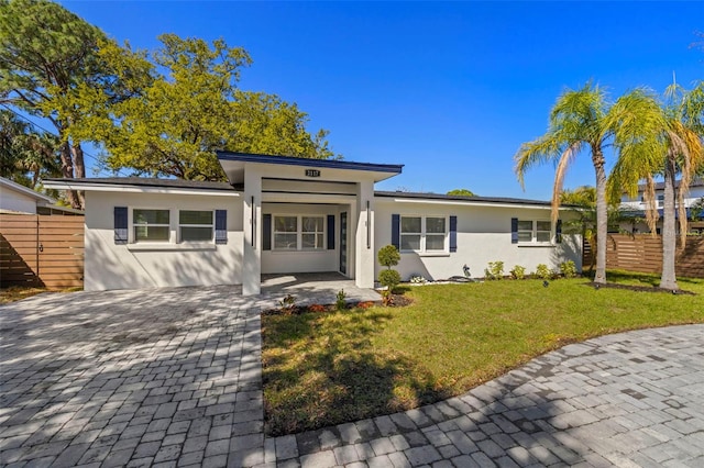 view of front of house featuring stucco siding, a front lawn, and fence