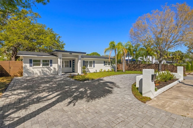 view of front of home featuring stucco siding, decorative driveway, a front yard, and fence