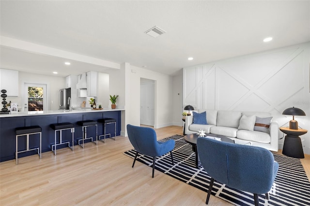 living area featuring recessed lighting, light wood-type flooring, baseboards, and visible vents