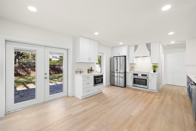 kitchen featuring custom exhaust hood, light wood-style flooring, stainless steel appliances, and light countertops