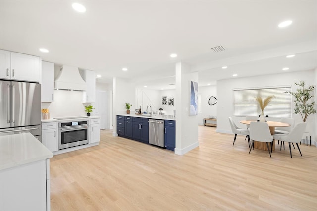 kitchen with visible vents, stainless steel appliances, light countertops, custom range hood, and light wood-style floors