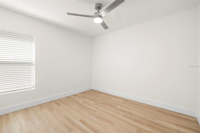 spare room with baseboards, light wood-style floors, and a ceiling fan