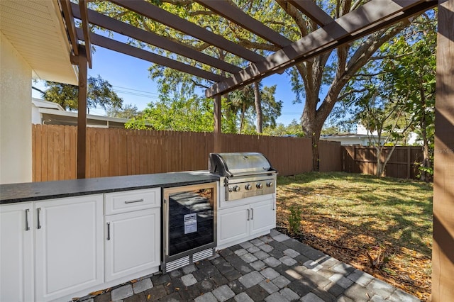 view of patio featuring area for grilling, beverage cooler, a pergola, a fenced backyard, and grilling area