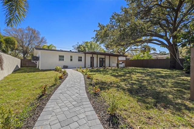 back of house with a yard, a fenced backyard, and stucco siding