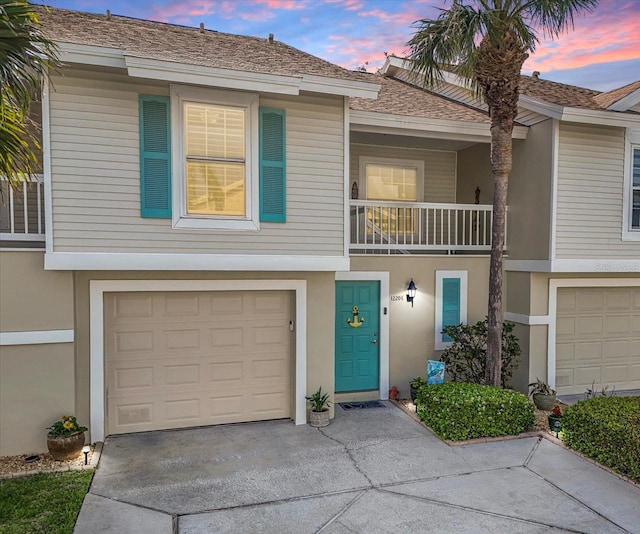 townhome / multi-family property featuring stucco siding, concrete driveway, a garage, and a shingled roof