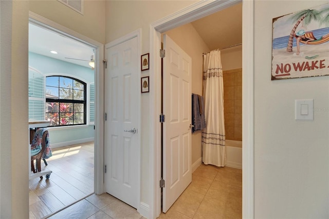 corridor with light tile patterned floors, visible vents, and baseboards