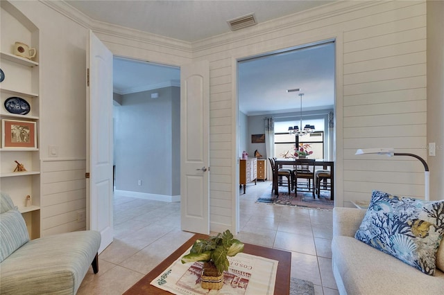 living area with light tile patterned floors, visible vents, built in shelves, and ornamental molding