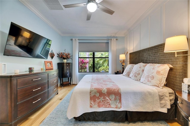 bedroom with light wood-style flooring, visible vents, ornamental molding, and a ceiling fan