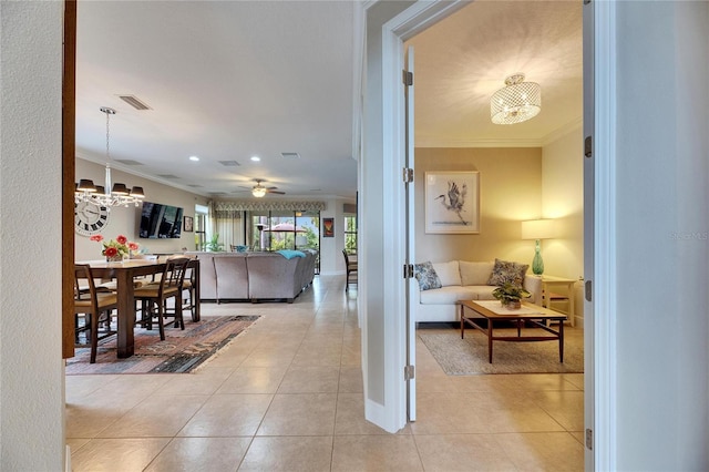 interior space featuring visible vents, ornamental molding, light tile patterned flooring, and ceiling fan with notable chandelier