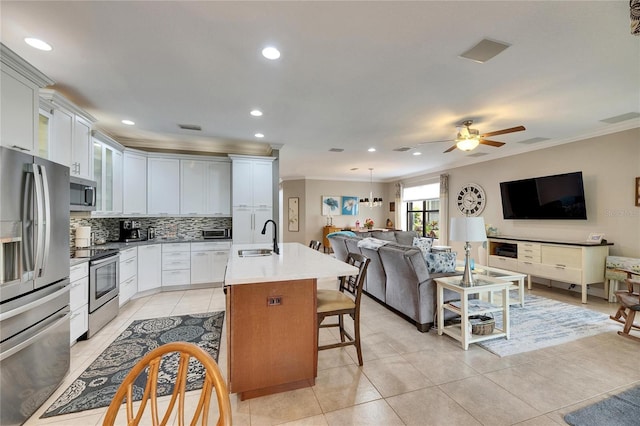 kitchen with a sink, decorative backsplash, stainless steel appliances, crown molding, and open floor plan