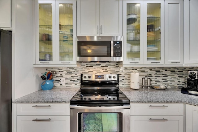 kitchen featuring decorative backsplash, light stone countertops, appliances with stainless steel finishes, and white cabinets