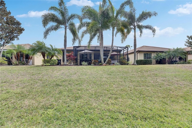 exterior space with stucco siding, a lawn, a lanai, and a tile roof