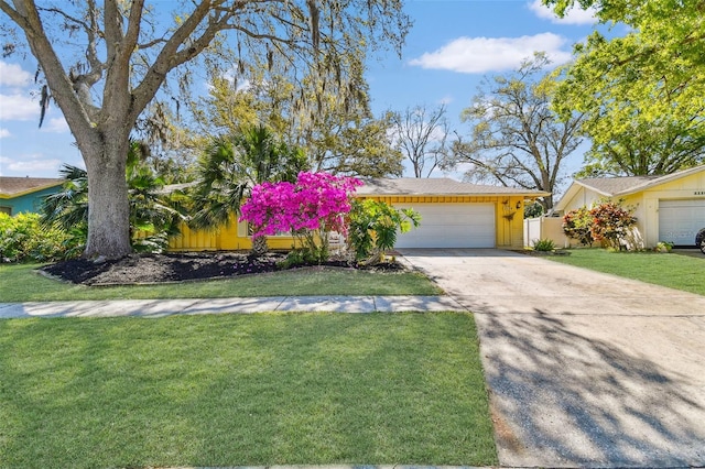 mid-century inspired home with an attached garage, concrete driveway, and a front lawn