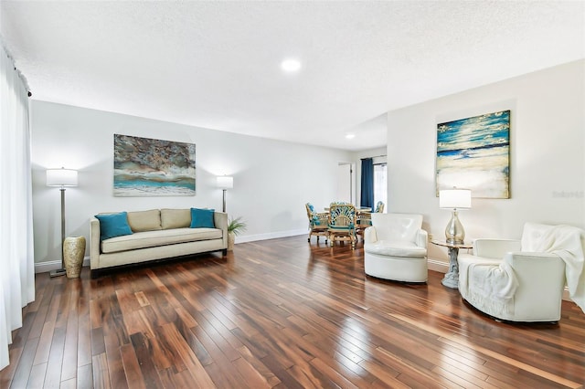 living area featuring hardwood / wood-style flooring, baseboards, and a textured ceiling