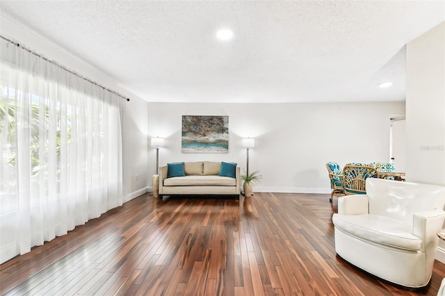 sitting room with a textured ceiling, baseboards, and hardwood / wood-style floors
