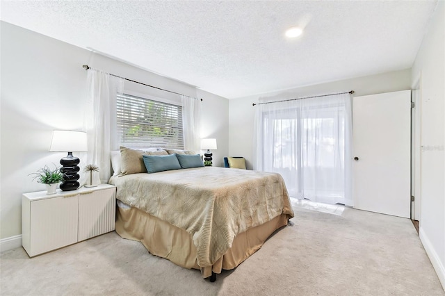 bedroom with light carpet, a textured ceiling, and baseboards