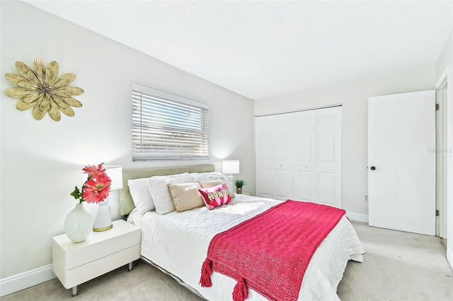 bedroom with a closet, light carpet, and baseboards