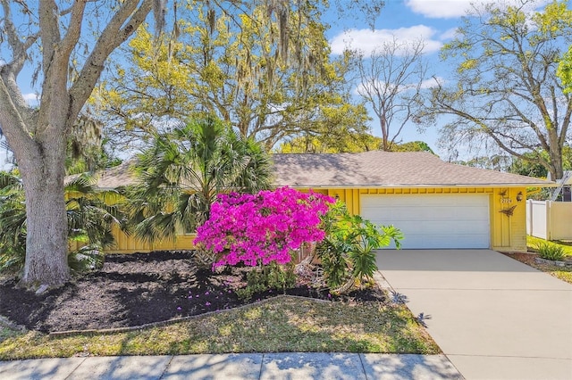 view of front of home with driveway, an attached garage, and fence