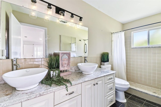 full bath featuring double vanity, tiled shower, and a sink