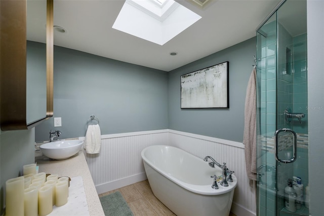 bathroom with a skylight, a wainscoted wall, a soaking tub, and a stall shower