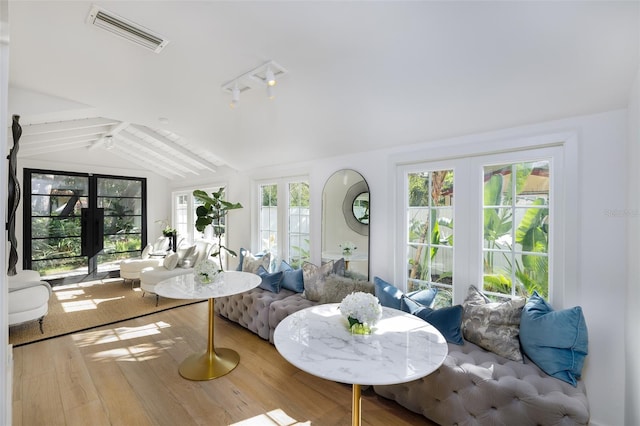 living area with lofted ceiling with beams, visible vents, wood finished floors, and french doors