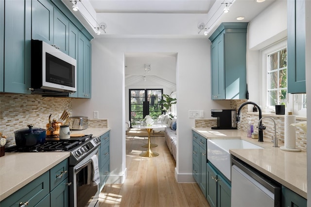 kitchen with white microwave, stainless steel range with gas cooktop, a sink, light wood-style floors, and dishwasher