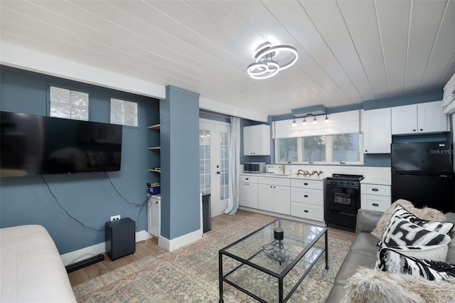 living area featuring french doors, plenty of natural light, baseboards, and light wood finished floors