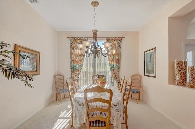 dining space with baseboards, a healthy amount of sunlight, light colored carpet, and a chandelier