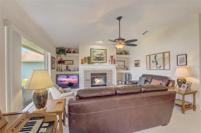 living area with visible vents, ceiling fan, light colored carpet, vaulted ceiling, and a fireplace